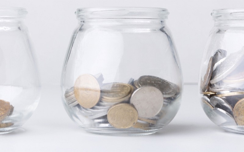 Three glass jars of coins, increasing in amount