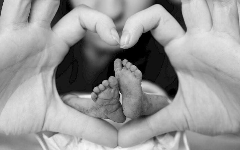 Atiny pair of feet encased in hands making a heart shape